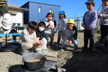 炊飯している焚火を見守る子ども達