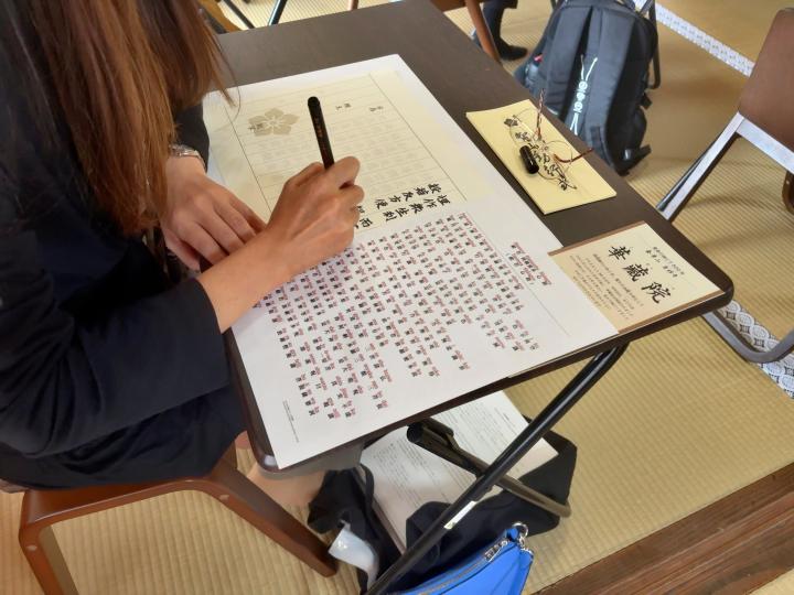 写経用紙に筆ペンで文字を写す様子